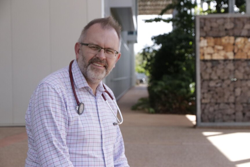 Dr Paul Lawton sits outside the Menzies health research facility.