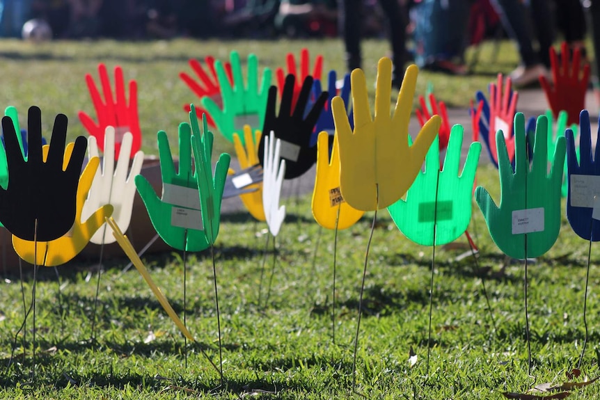 Hand cut outs are staked in the ground to represent multiculturalism and reconciliation.