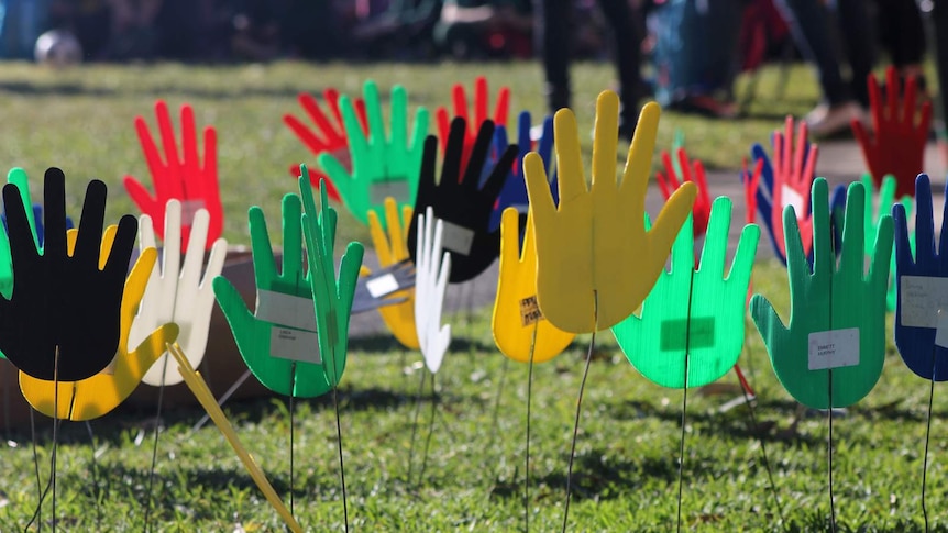 Hand cut outs are staked in the ground to represent multiculturalism and reconciliation.