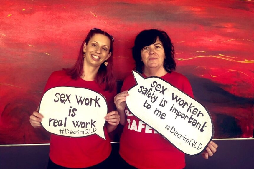 Two women hold signs that state sex work is real work.