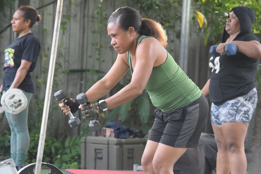 A Papua New Guinean woman is working out lifting hand weights.