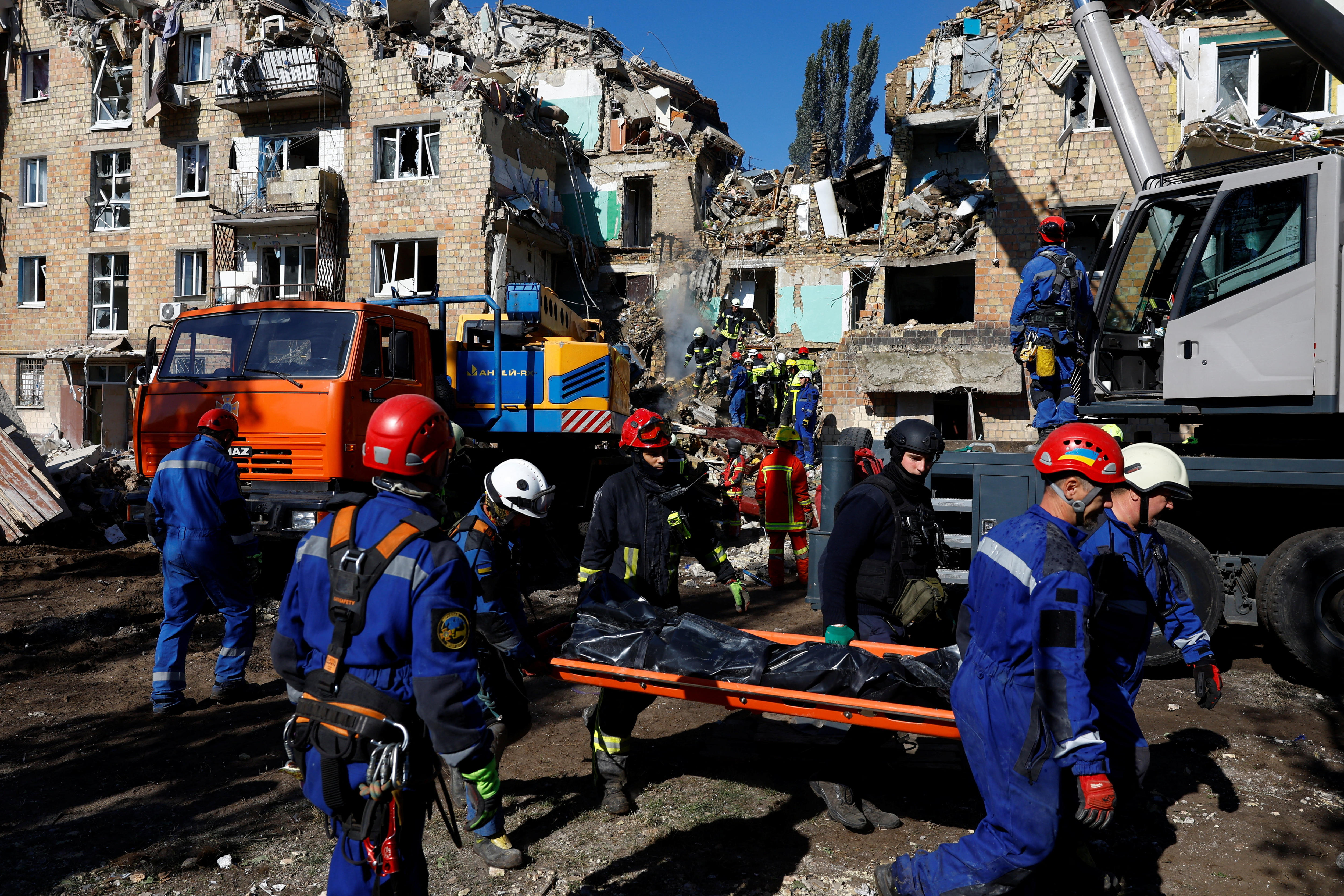 Emergency services workers carry a stretcher away from damaged buildings.