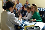 a woman and child speak to a medical worker over a desk at an iodine tablet distribution point