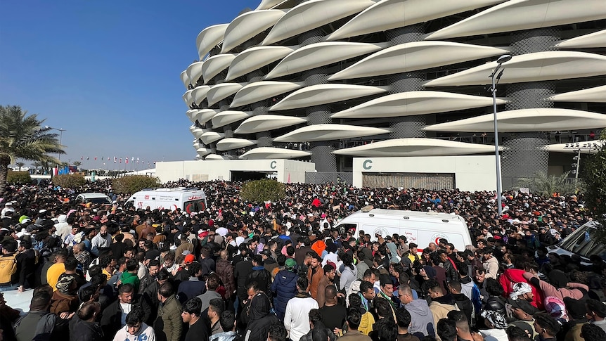 Two ambulances try to get through thousands of soccer fans outside the Basra International Stadium.