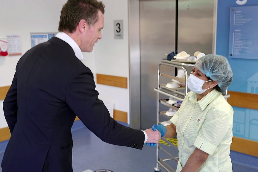 the premier of new south wales shakes a cleaner's hand in a hospital