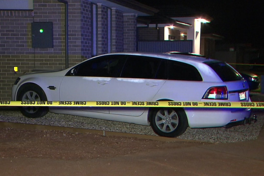 A white station wagon next to a house with crime scene tape