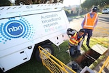 Workers installing NBN fibre to the node next to NBN truck