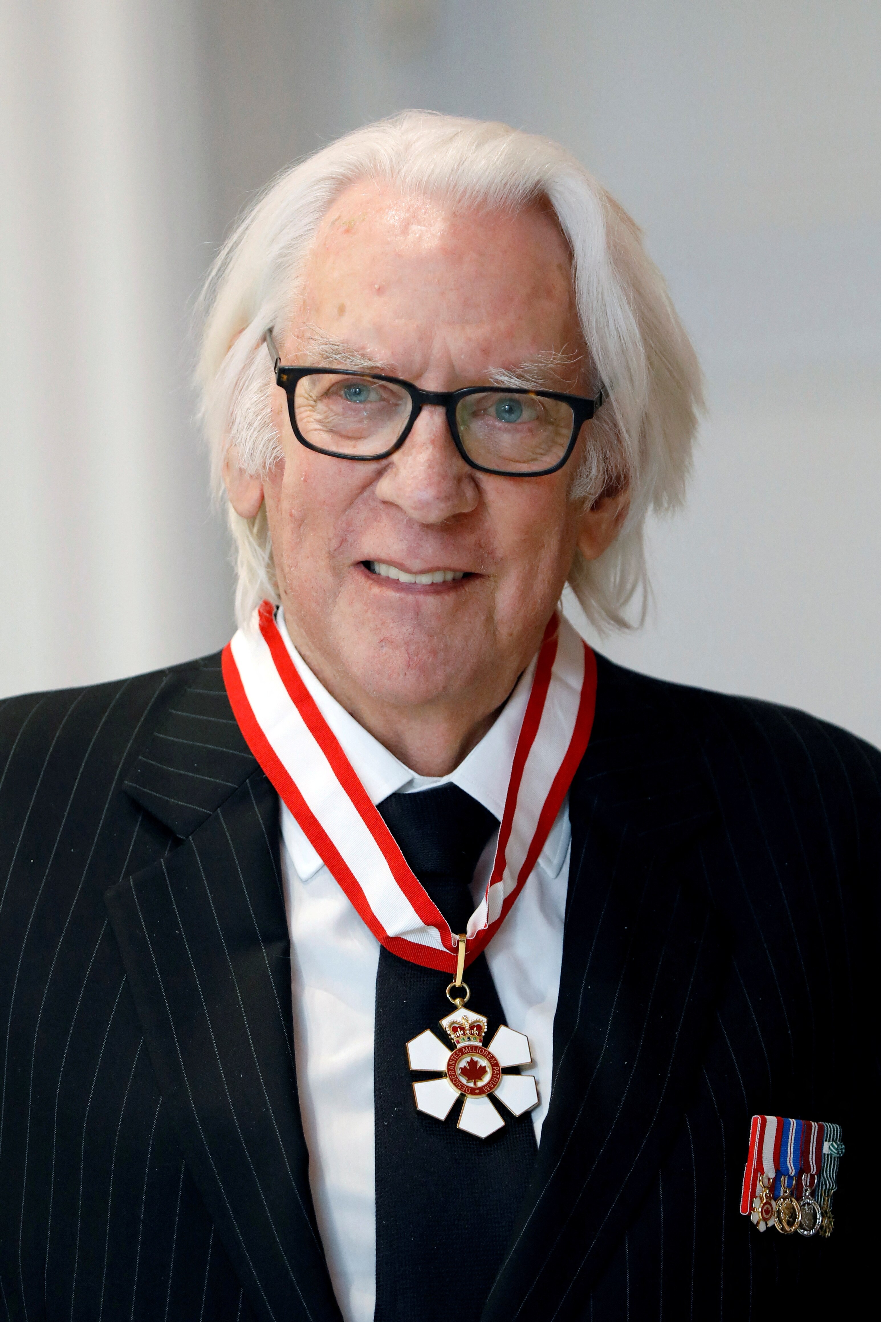 Donald Sutherland smiling for the camera with a medal around his neck
