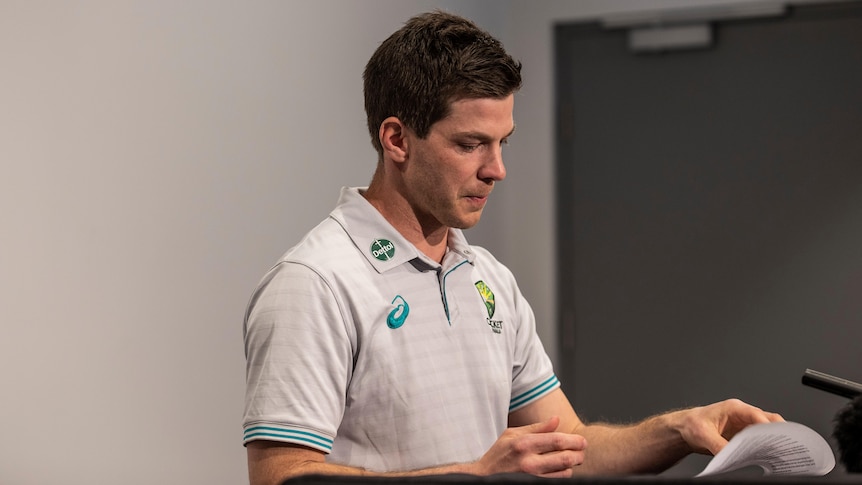 Tim Paine looks at a piece of paper.