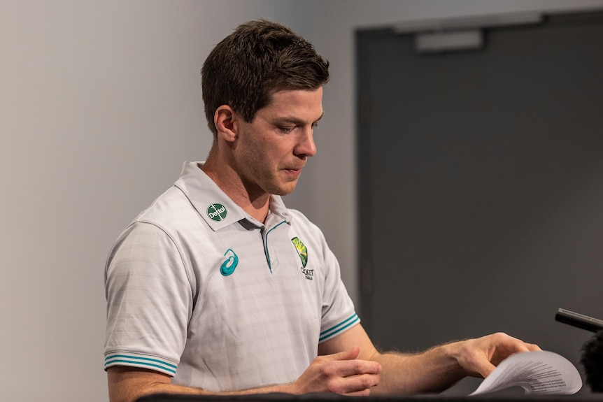 Tim Paine looks at a sheet of paper.