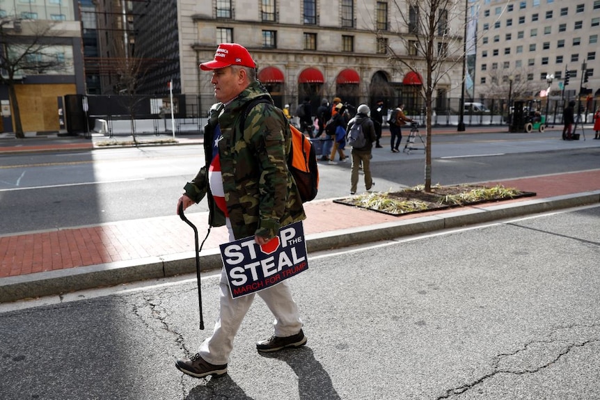 A lone former President Donald Trump supporter walks down a Washington street.