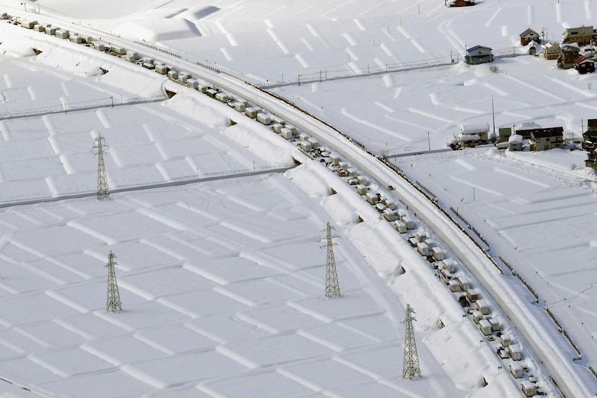 An aerial view of tiny cars in a row topped with snow
