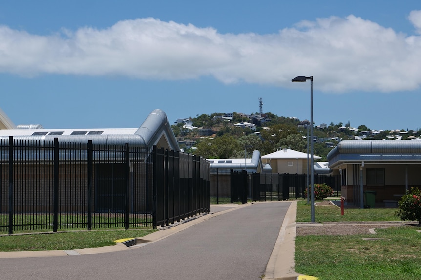 Red brick buildings surrounded by high black fences.