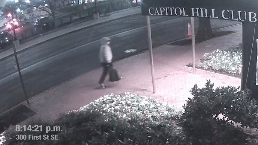 Security footage shows a person wearing a grey hoodie and carrying a backpack walking past the Capitol Hill Club