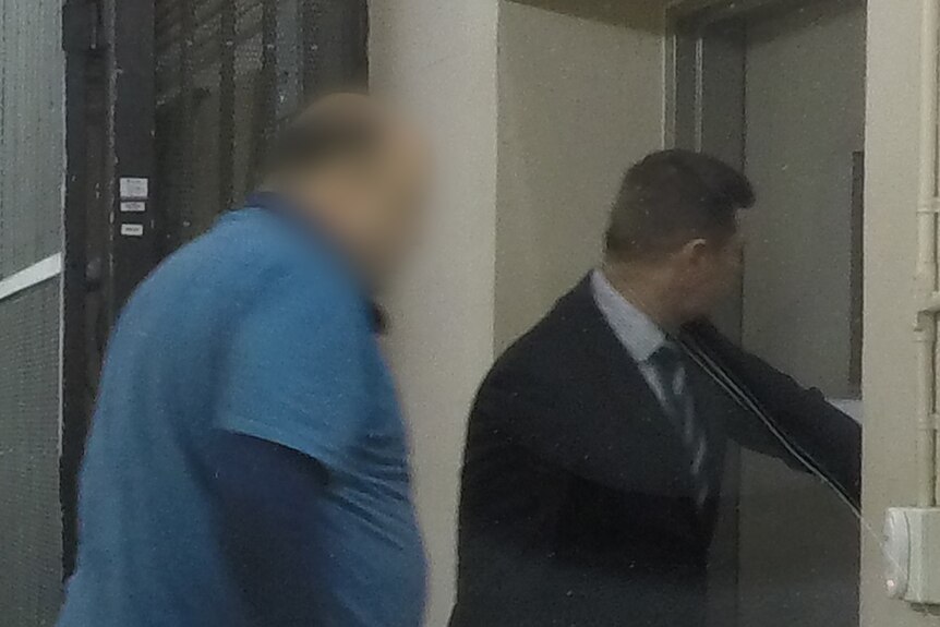 A man with a blurred face walks through a door