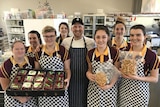 Matt Golinski smiling at the camera surrounded by students holding up strawberries and gooseberries.