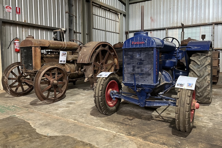 Two antique tractors in a shed.