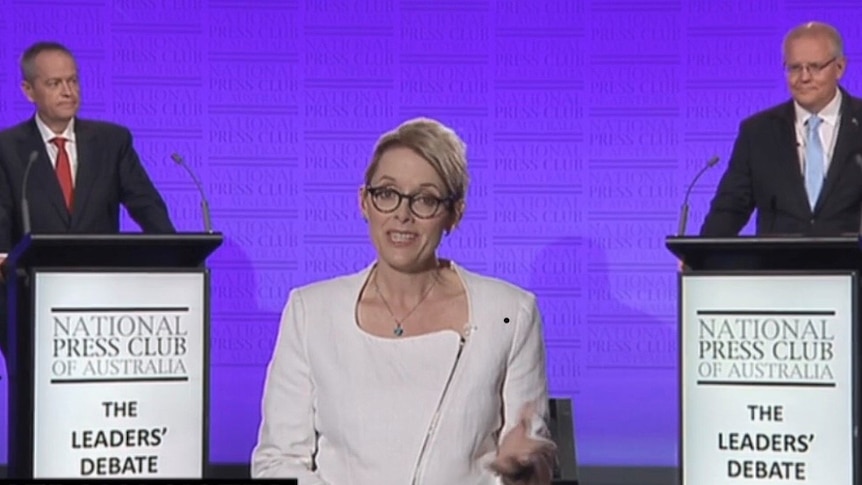 Woman standing between two men standing at lecterns with National Press Club of Australia The Leaders' Debate written on them.