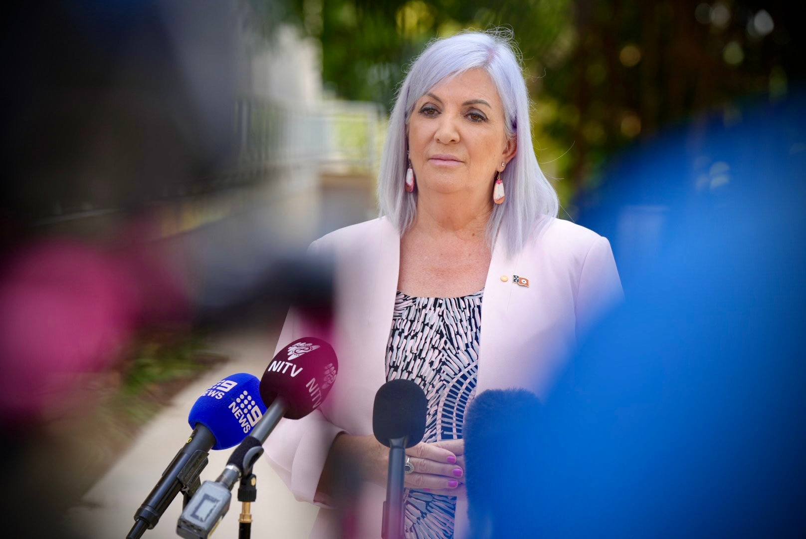 Robyn Cahill wears a pink blazer and serious facial expression as she speaks to media outside parliament house in Darwin.