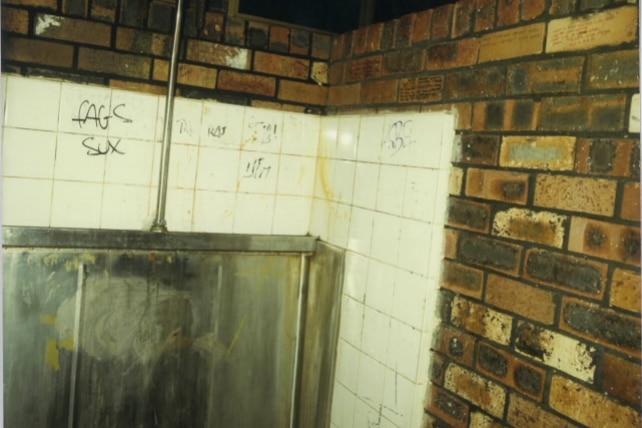 Inside a toilet block with derogatory homophobic words on the walls