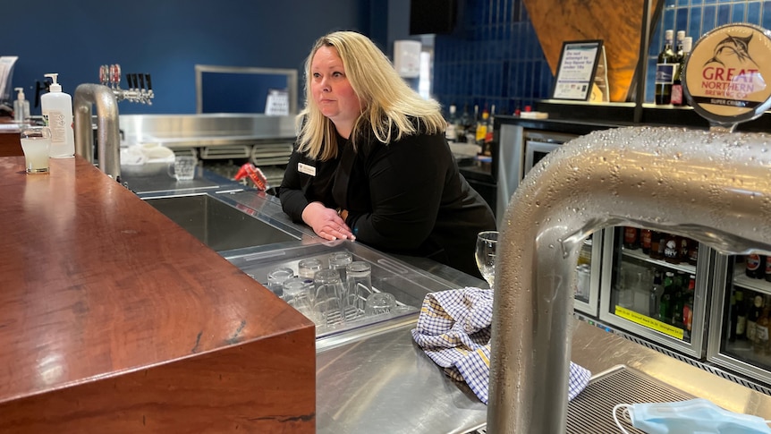 A woman leaning on a sink behind a bar.