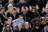 People show a sign and writing on their palms reading Je suis Charlie