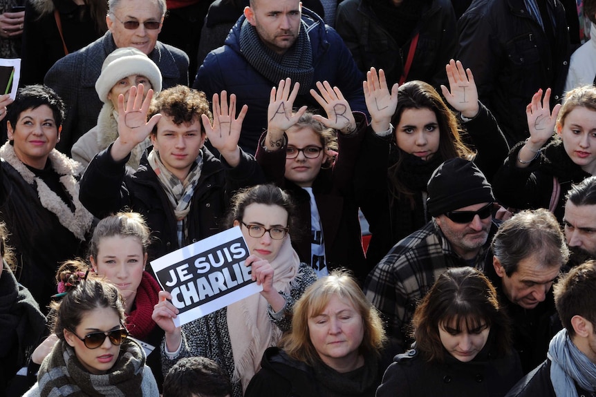 People show a sign and writing on their palms reading Je suis Charlie