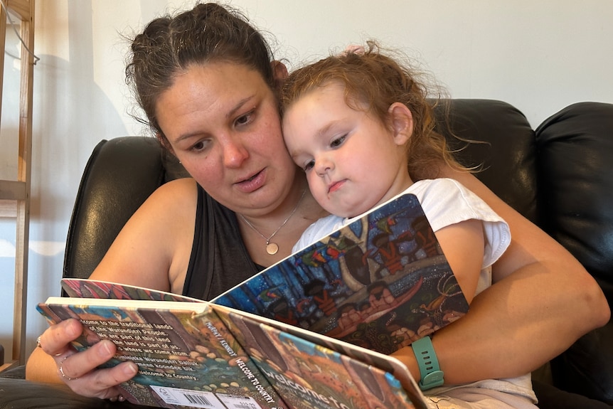 A mum and her daughter reading a book.