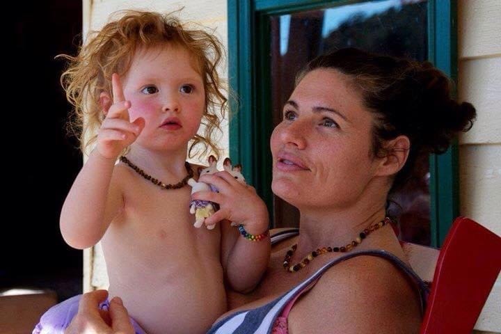 A woman is seated holding a toddler girl