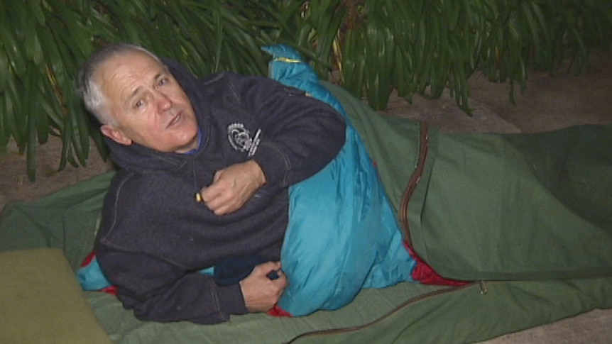 An ABC camera crew wakes Communications Minister Malcolm Turnbull at the CEO Sleepout.