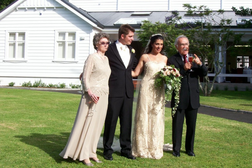 A couple smiling and posing for a photo on their wedding day.