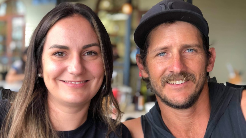 A close up of woman with long brown hair and man with hat and goatee. They are smiling