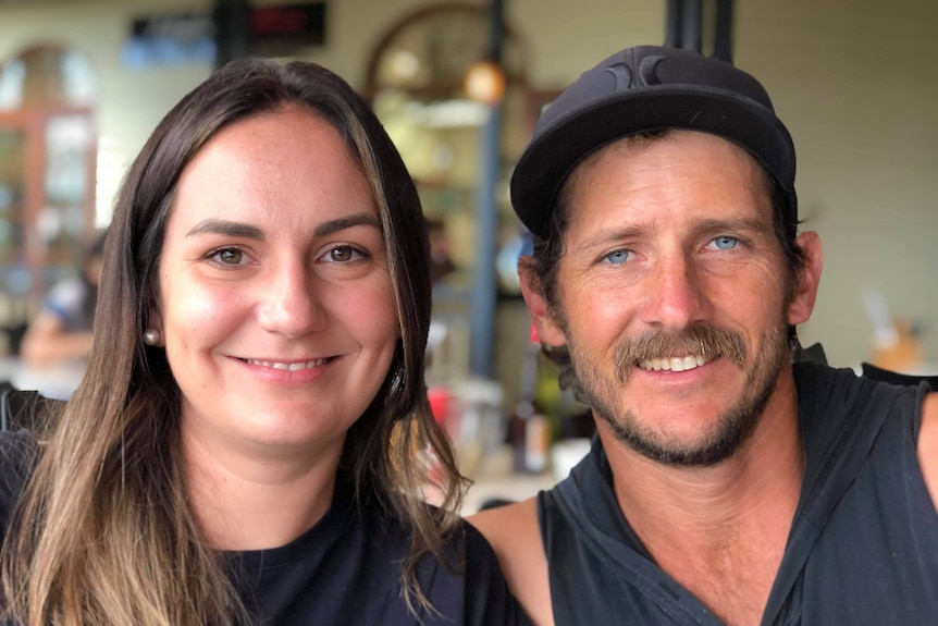 A close up of woman with long brown hair and man with hat and goatee. They are smiling