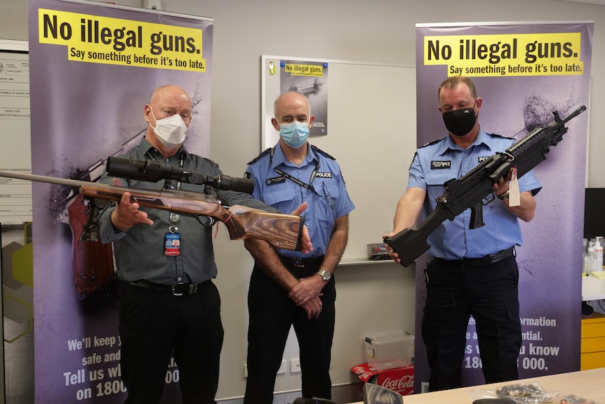 Police officers with a display of seized firearms.  