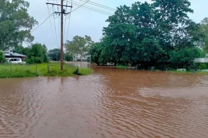 A flooded dirt road winding through houses in a remote community.