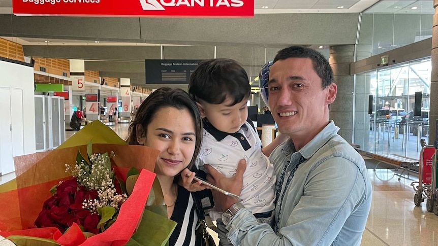 Sadam Abudusalamu poses for a photo with his wife and child after their arrival in Australia