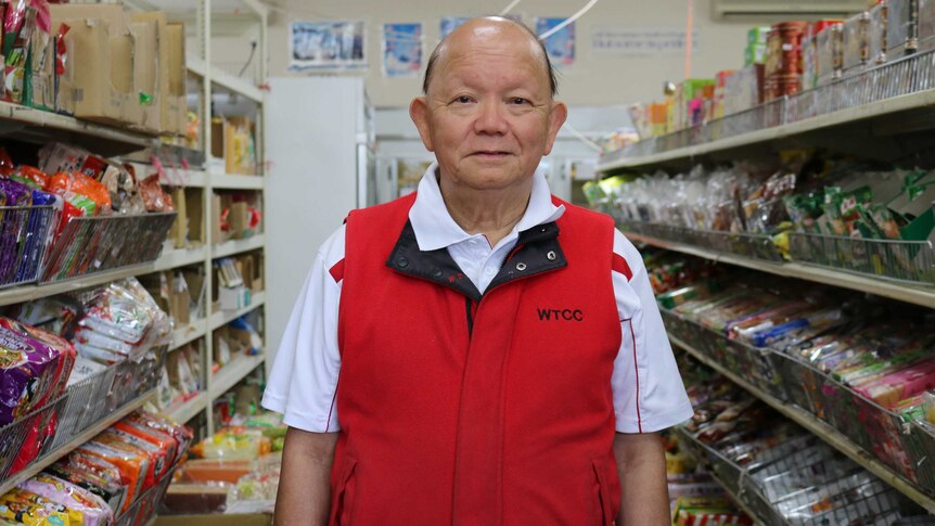 Vincent Liu stands in between rows of packaged food in his Asian grocery shop.