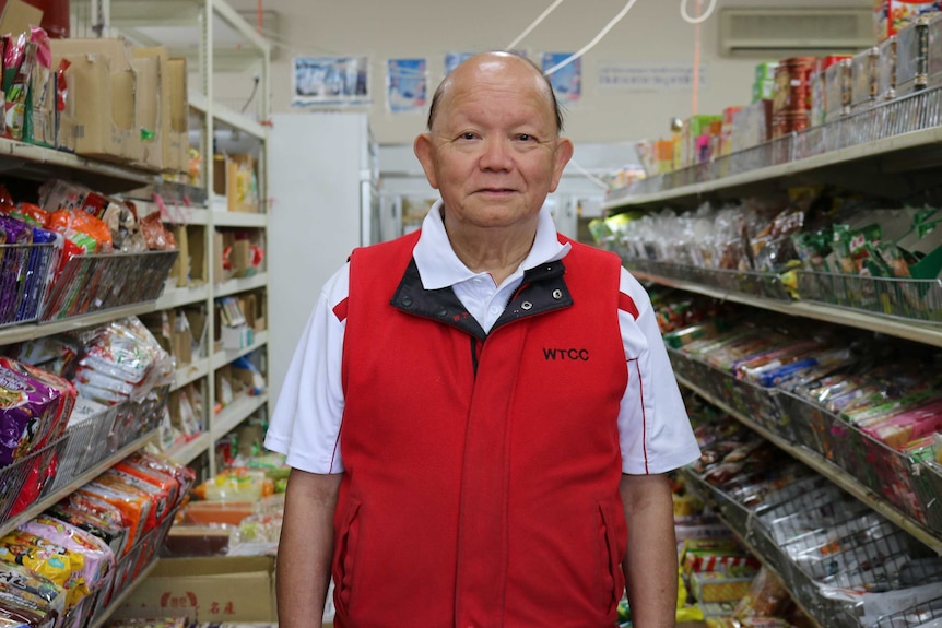 Vincent Liu stands in between rows of packaged food in his Asian grocery shop.