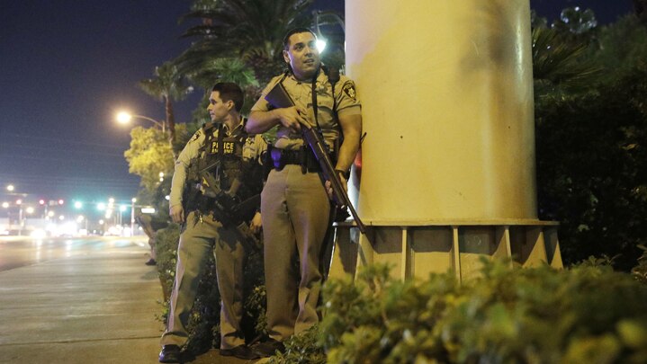 Police officers take cover near the scene of a shooting near the Mandalay Bay resort and casino on the Las Vegas Strip