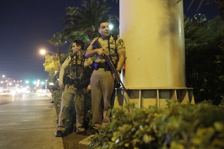 Police officers take cover near the scene of a shooting near the Mandalay Bay resort and casino on the Las Vegas Strip
