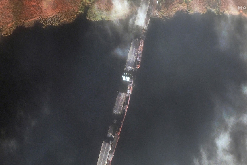 A satellite image shows the span of a damaged Antonovskiy bridge that fords a large body of water.