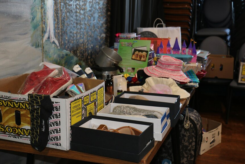 A table is filled with donations including shoes, hats, toys and books. 
