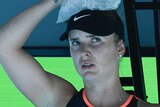 A seated Elina Svitolina looks concerned while holding a bag of ice onto the top of her head