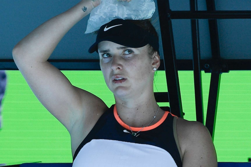 A seated Elina Svitolina looks concerned while holding a bag of ice onto the top of her head