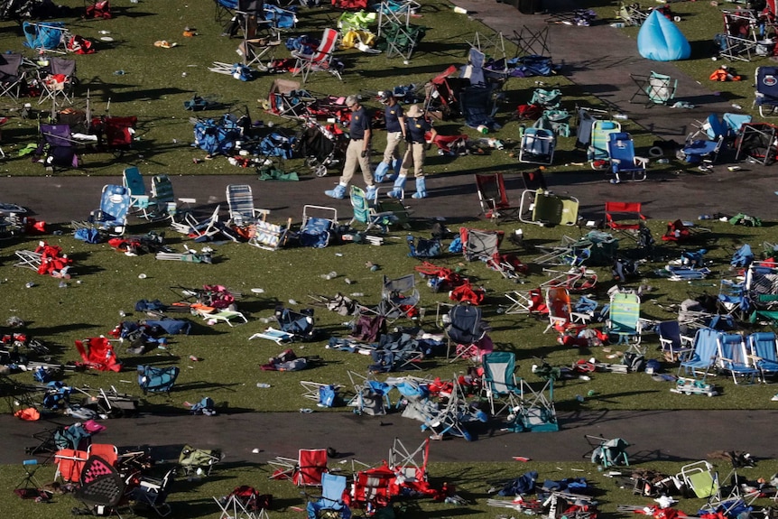 FBI agents walk among the toppled chairs and debris in the concert grounds