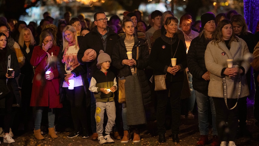 A crowd of people gathered in a park for a candlelight vigil.