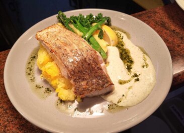 A photo of a plate of salmon with some mash potato and brocollini