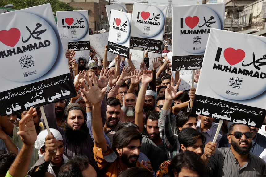 People holding placards and protesting the derogatory comments against the Prophet.