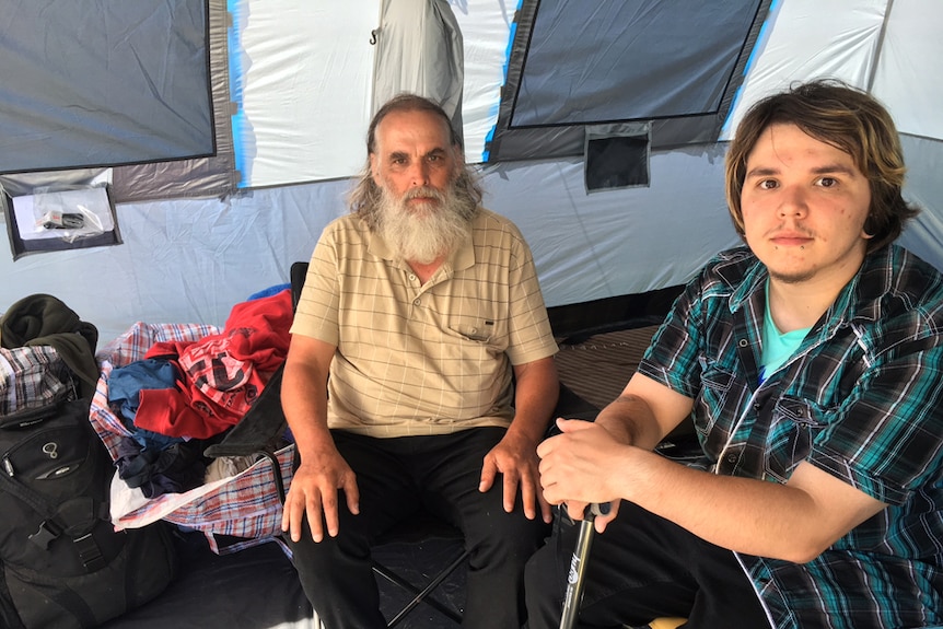 Queensland man Michael Reid and son sit in their tent