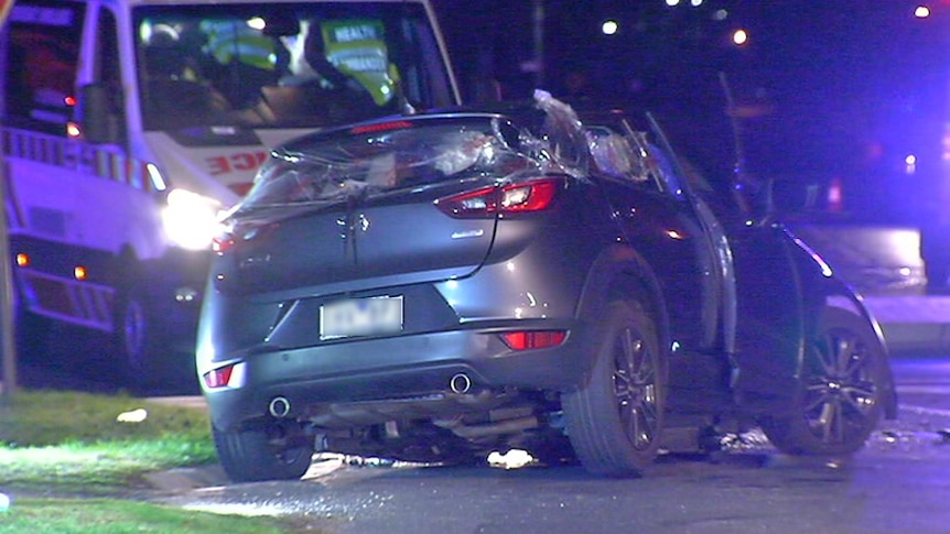 A smashed grey hatchback car with an ambulance parked behind it.